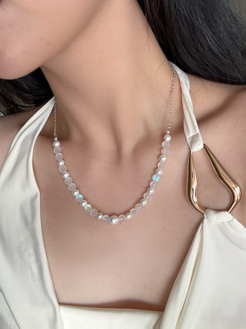 Necklace with beaded chain worn by a person in a white top