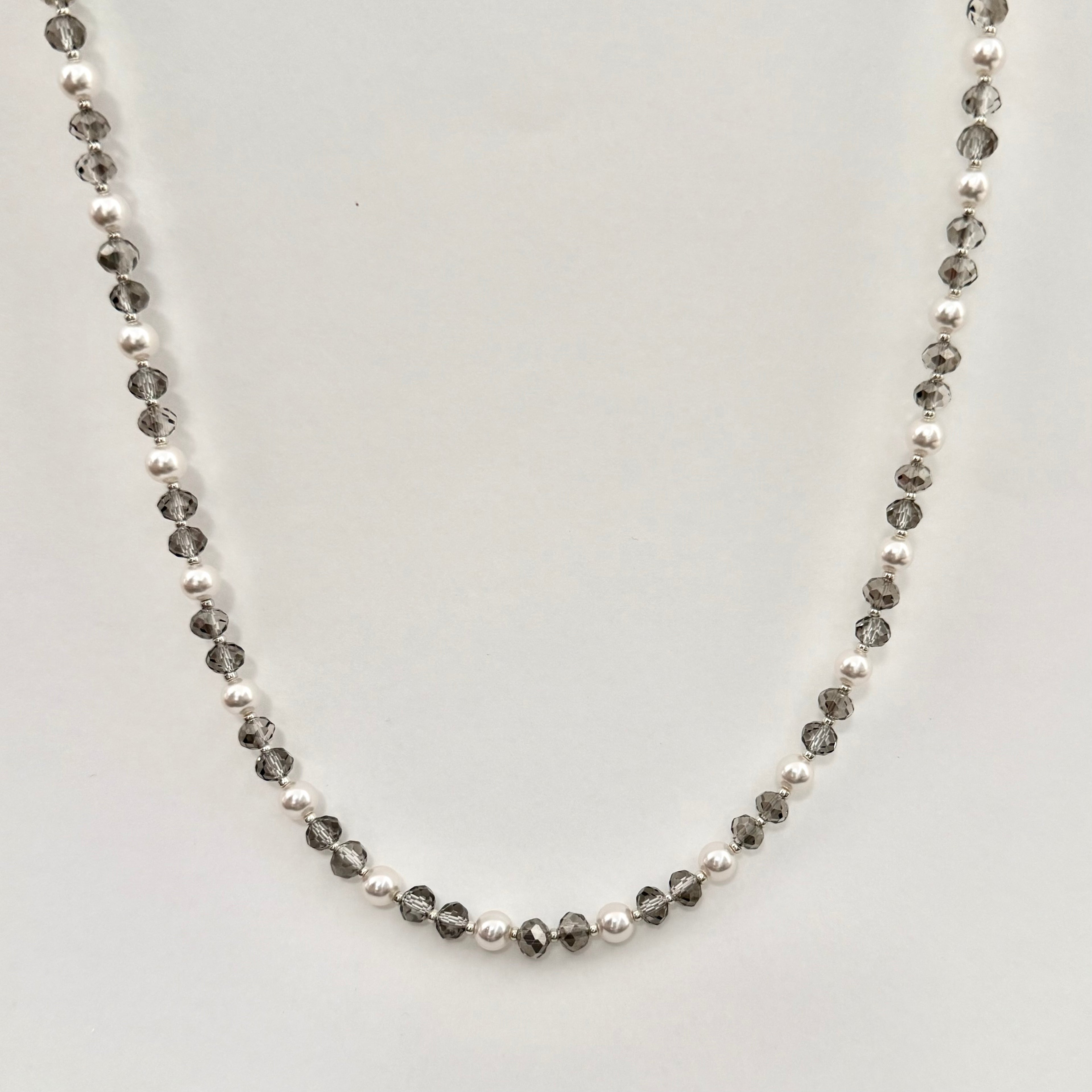Necklace with alternating black and white beads on a light gray background