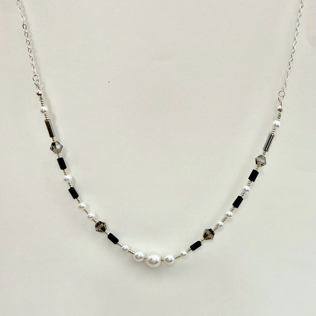 Necklace with pearls and black beads on a light gray background