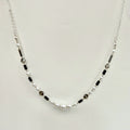 Necklace with pearls and black beads on a light gray background