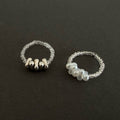 Two silver rings with bead detailing on a black background