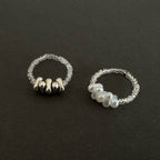 Two silver rings with bead detailing on a black background