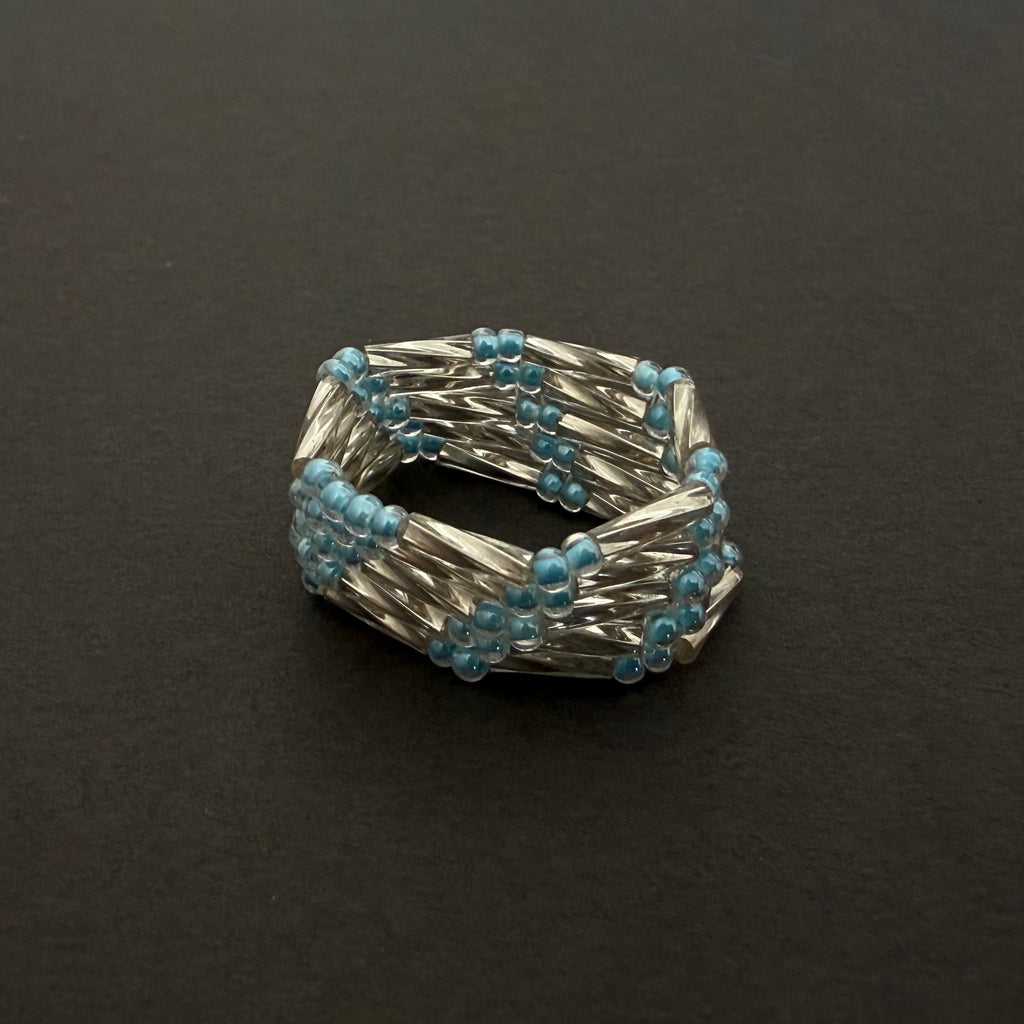 Silver and blue beaded ring on a dark background
