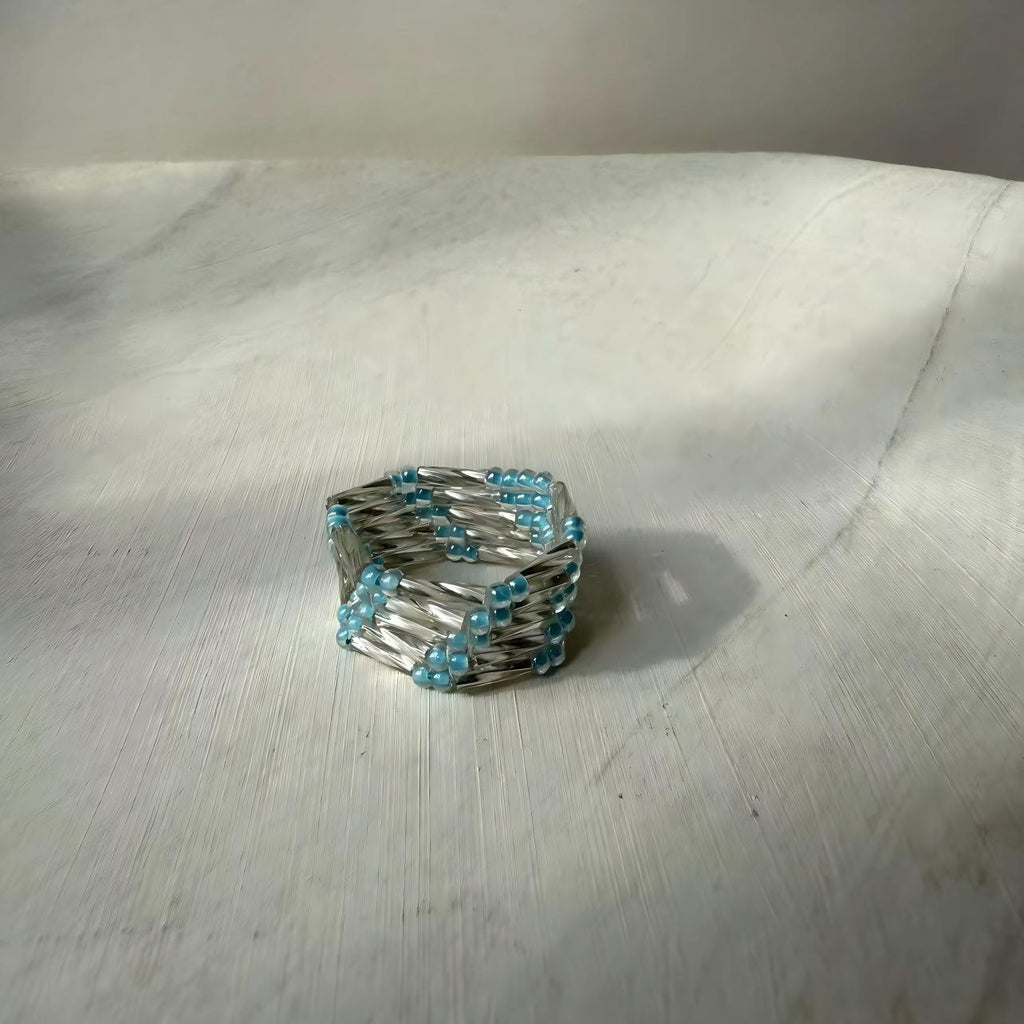 Silver ring with blue beads on a light gray surface