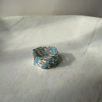 Silver ring with blue beads on a light gray surface